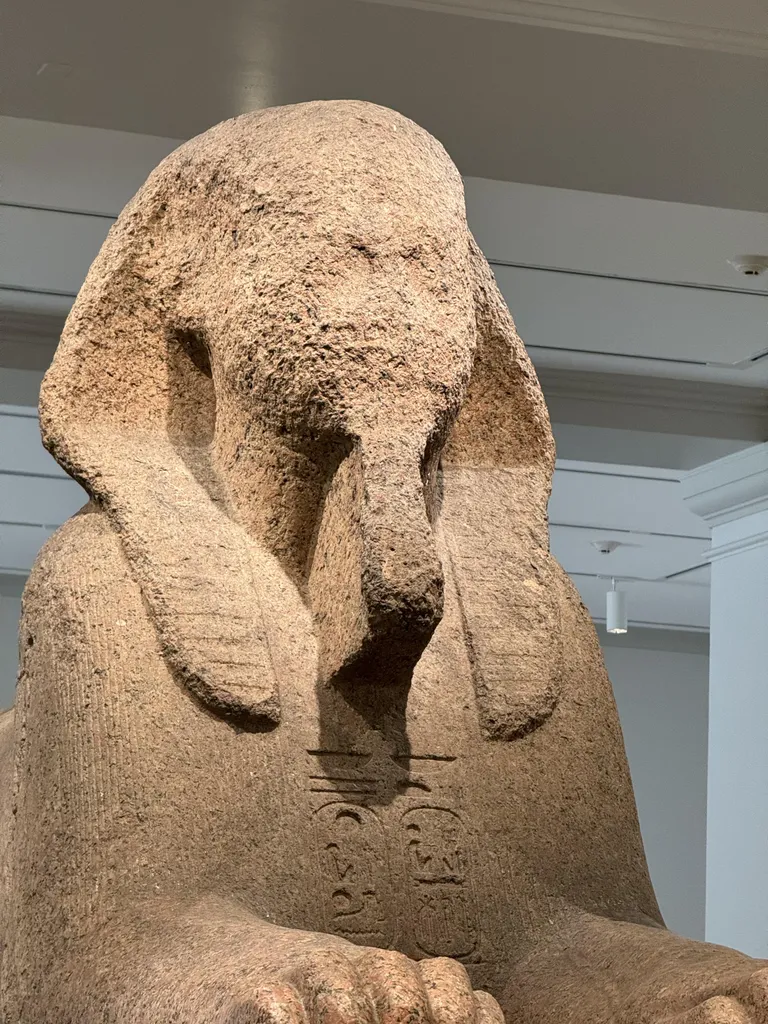 A sphinx whose face has been effaced by time and the elements.
